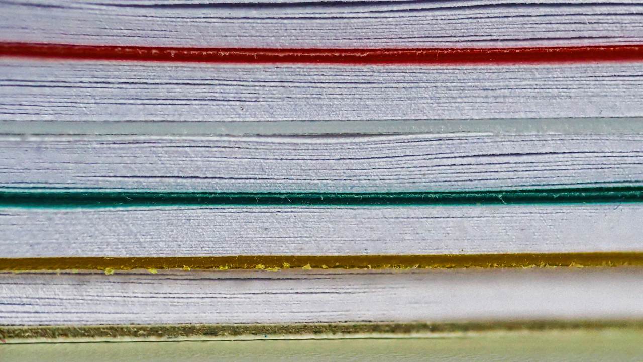 A close view of the edges of stacked sheets of paper separated by red, green and yellow divider sheets.