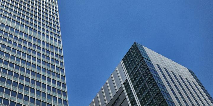 Two modern office towers side by side against a clear blue sky.